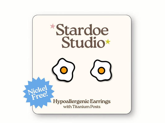Small oval white egg earrings with realistic shell texture and smooth surface, featuring classic breakfast food design that food lovers and cooking enthusiasts adore, representing farm fresh ingredients and kitchen culture, secured with hypoallergenic titanium posts, perfect for kids who love food themed jewelry and culinary accessories that celebrate everyday breakfast essentials