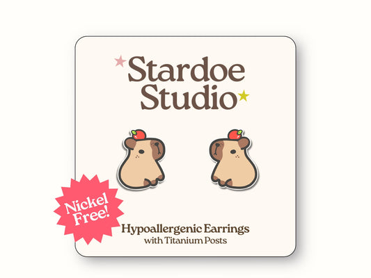 Little capybara stud earrings. These earrings are specifically two identical adorable capybaras with red apples on their heads. These earrings are handmade with hypoallergenic titanium posts animal jewelry for kids and adults.