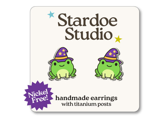 Little wizard frog stud earrings featuring a cute frog wearing a purple wizard hat. These earrings are handmade with hypoallergenic titanium posts fantasy jewelry for kids and adults.
