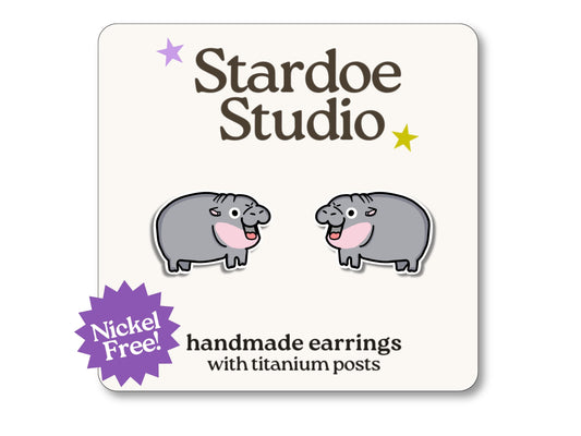 Little Moo Deng hippo stud earrings featuring a cute pink hippo design inspired by the viral meme. These earrings are handmade with hypoallergenic titanium posts animal jewelry for kids and adults.